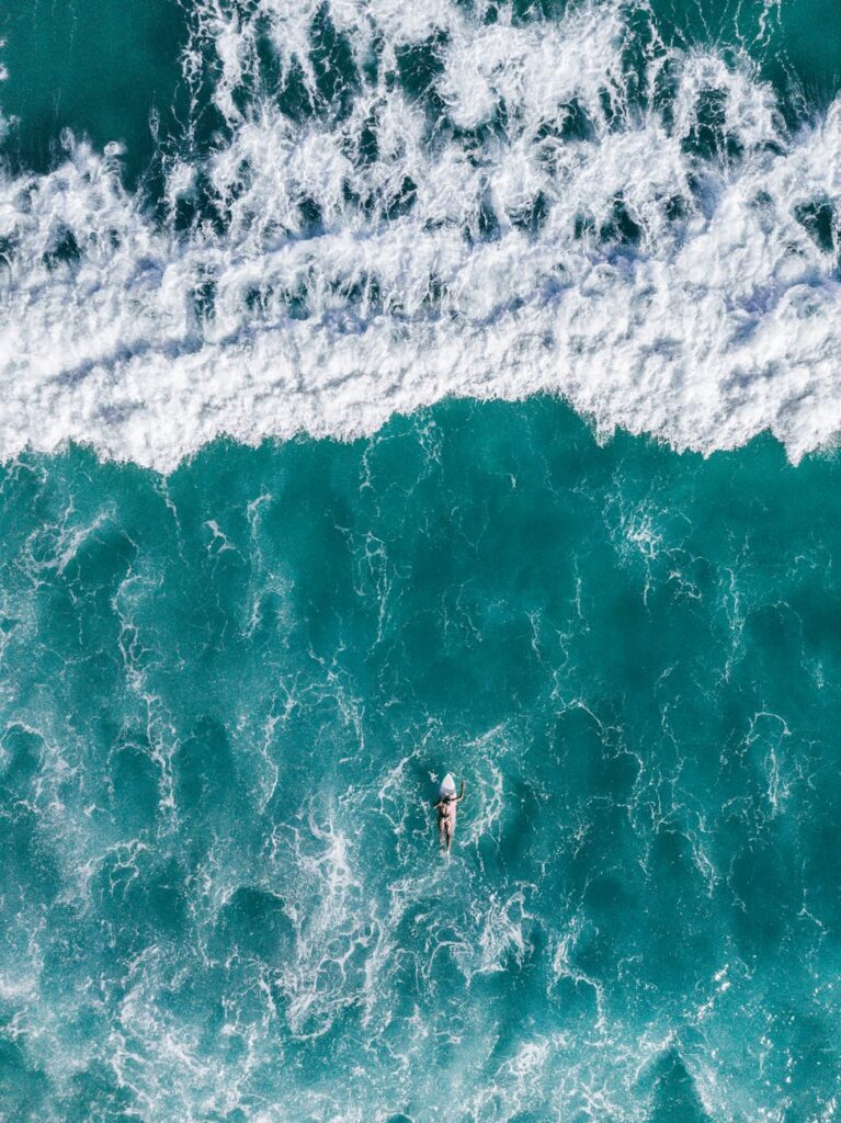 Stunning aerial shot of a lone surfer riding vibrant turquoise waves in Brazil's pristine waters.